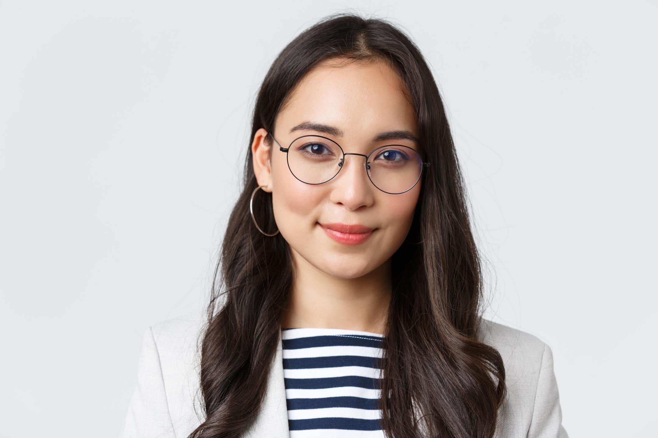 A professional headshot of a woman smiling wearing a striped blue shirt and blazer.